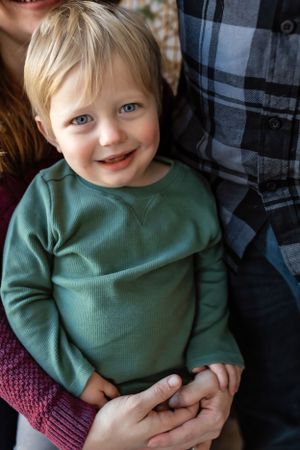 Young child wearing green sweater smiles warmly while being held in a holiday setting.
Janesville, WI
Brodhead, WI