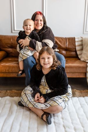 A cozy family portrait on a brown leather couch and white rug in a warmly lit living room interior. Janesville, WI
Brodhead, WI
