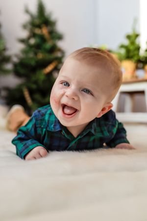 Smiling baby in plaid shirt lying on carpet with Christmas tree in background during holiday photo session. Janesville, WI
Brodhead, WI