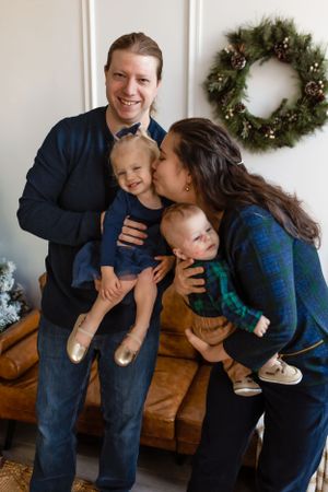 A family wearing blue sweaters poses for a holiday photo with a wreath hanging on the wall behind them. Janesville, WI
Brodhead, WI