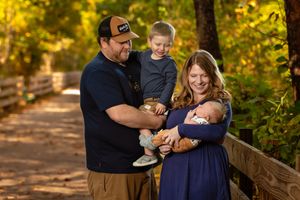 Family enjoying a warm autumn day together in a sunlit wooded area during a photo session.