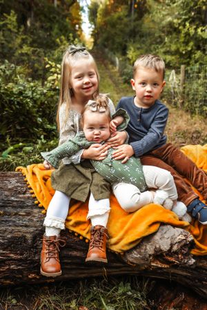 Children sitting together on a fallen log with an orange blanket in an autumn forest setting.
Janesville, WI
Brodhead, WI