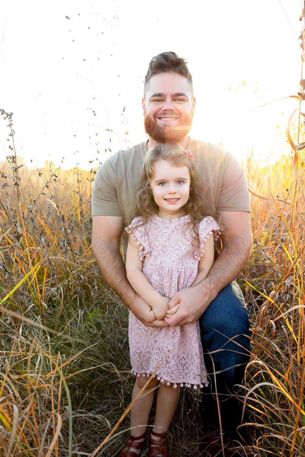 Warm sunset portrait of two people embracing in a natural field setting.