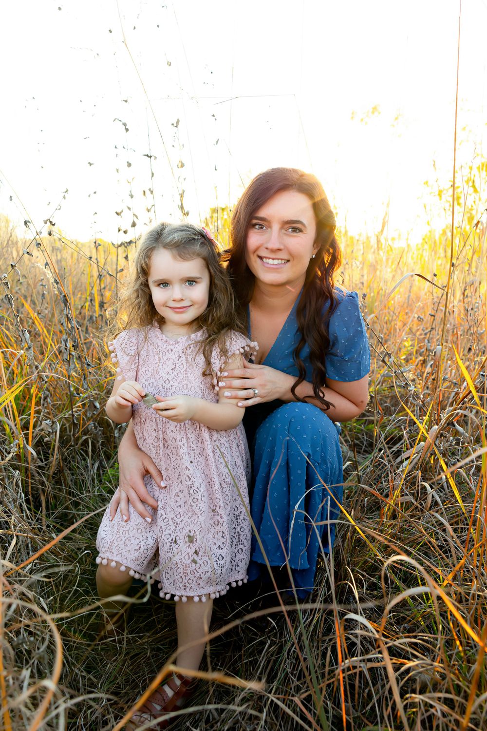 Loving outdoor portrait of two people among tall grass at golden hour.