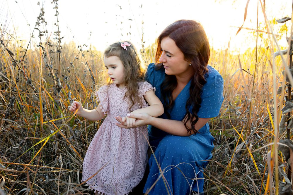 Tender moment between two people in a golden field at sunset.