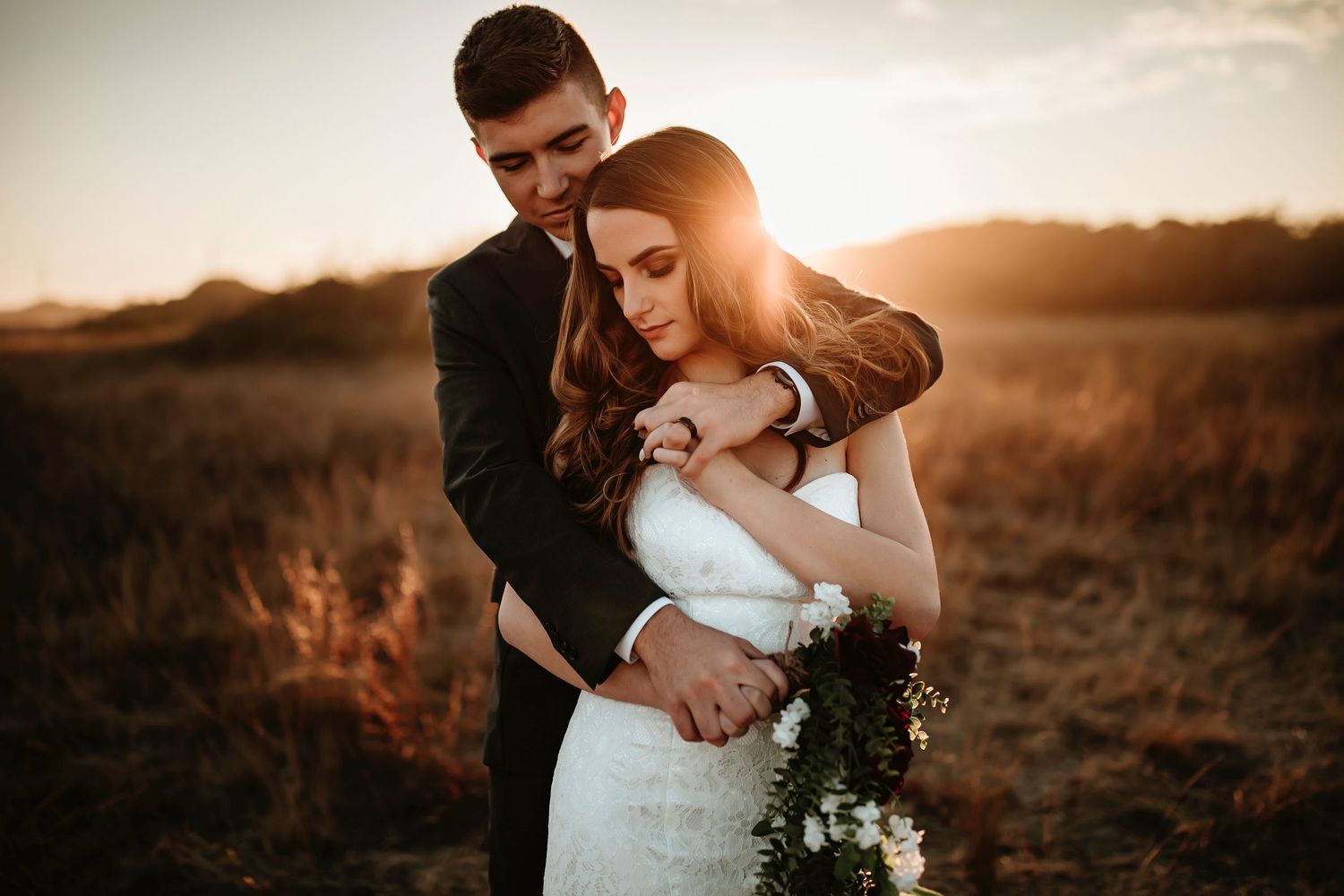 A romantic sunset moment captured between a couple in a field with beautiful golden light.