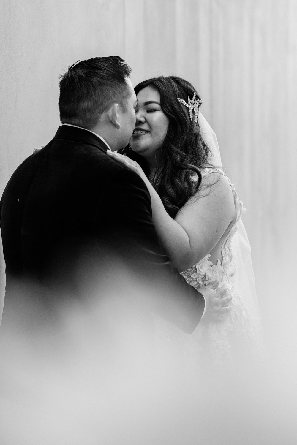 An intimate black and white portrait of a wedding couple sharing a tender moment.