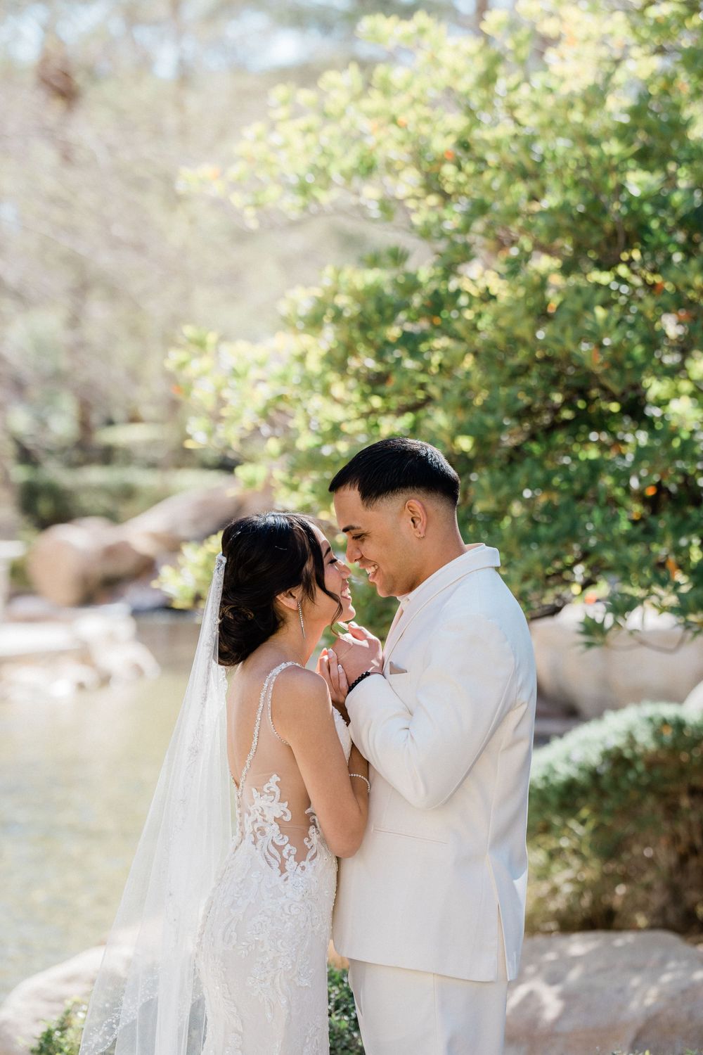 Couple in wedding attire embraces tenderly in lush garden setting.