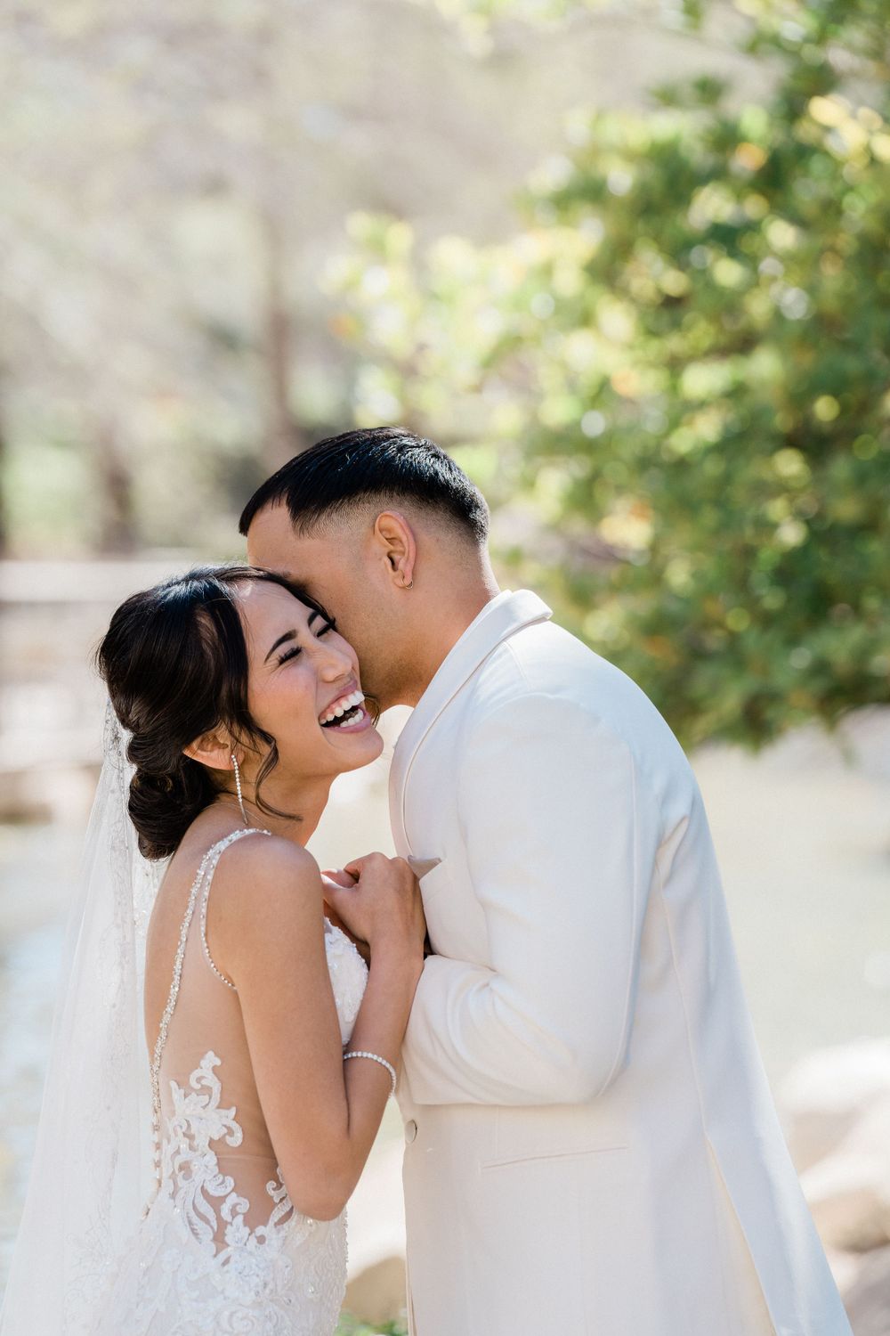 Wedding couple sharing an intimate moment outdoors with lush greenery in the background.
