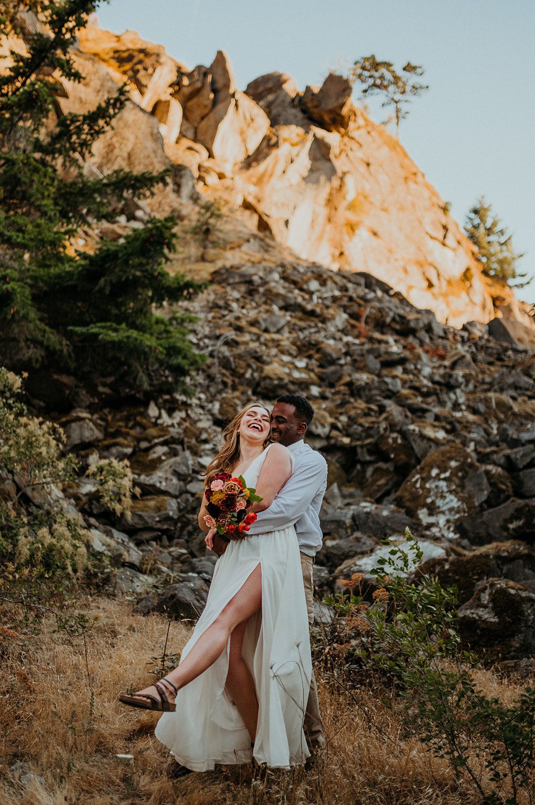 Joyful couple shares playful moments during their sunset mountain wedding photoshoot.