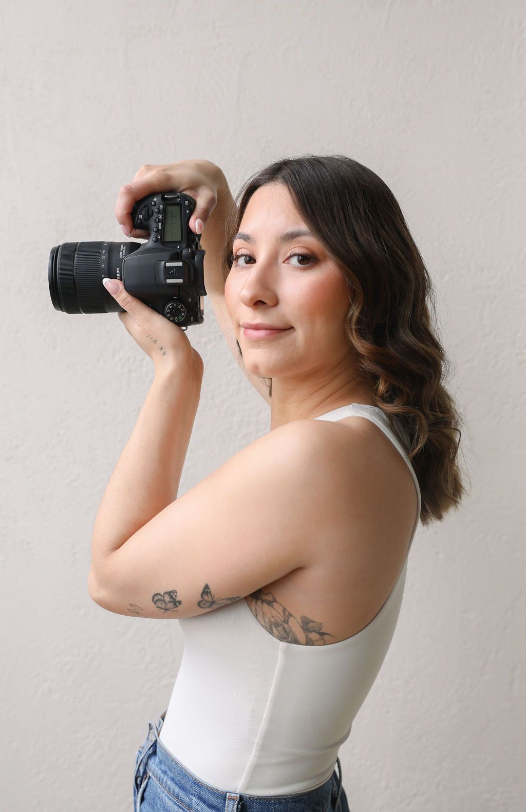 Female photographer holding her camera at eye level. She is looking frontwards.
