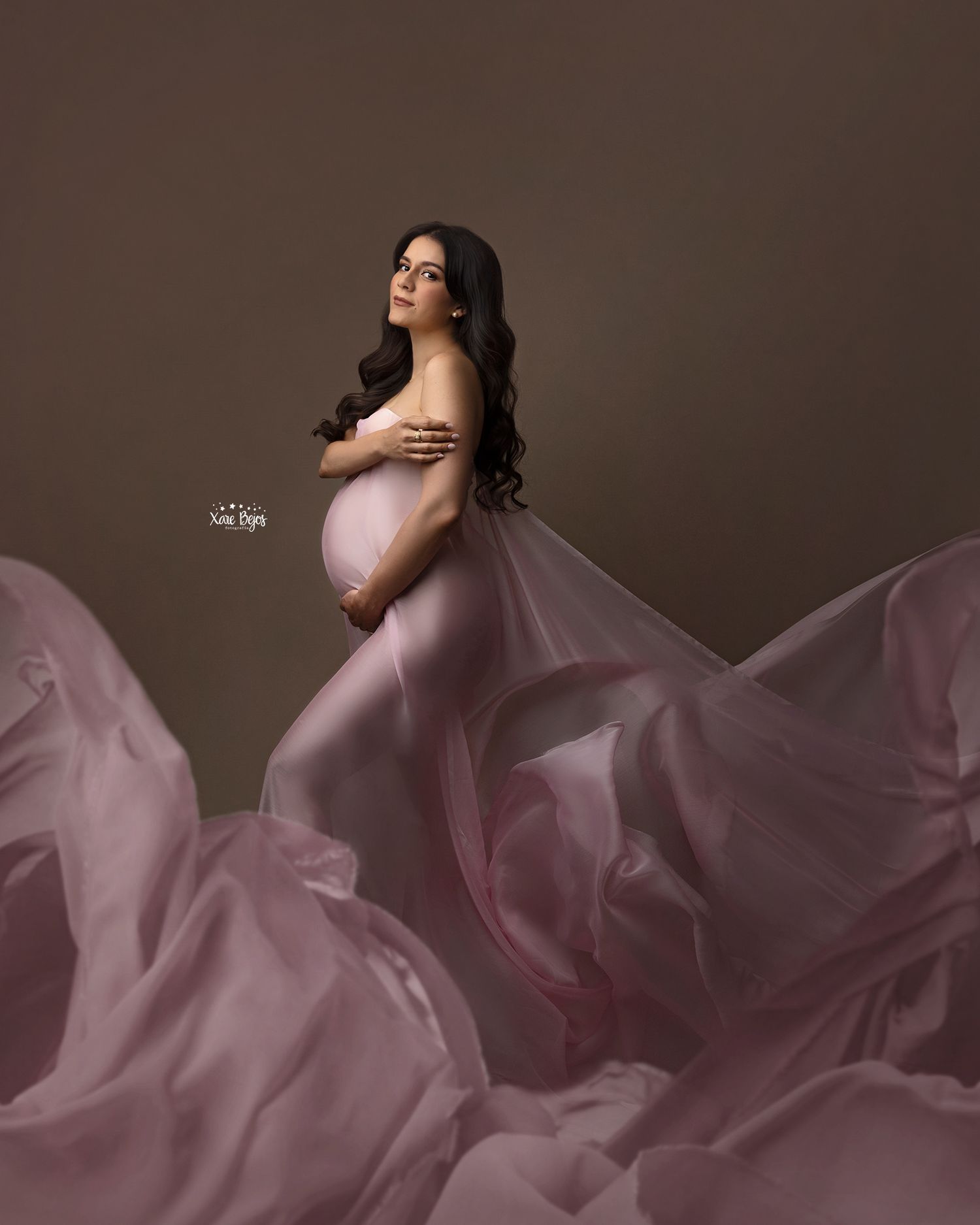 Graceful pose with billowing mauve fabric creating dynamic movement in studio setting.