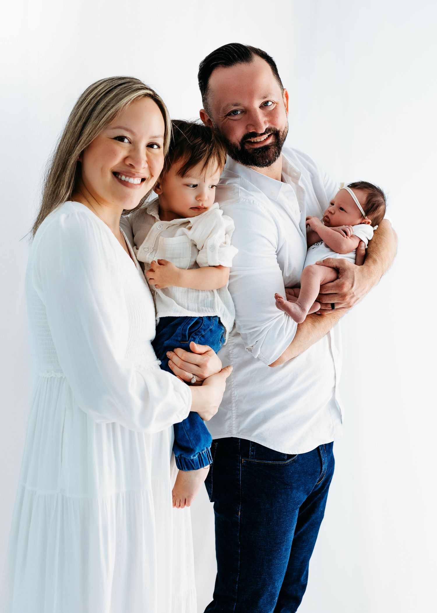 A family wearing white and denim poses together against a light background for a studio portrait.
Rashinphotography-Nova photographer- DMV
