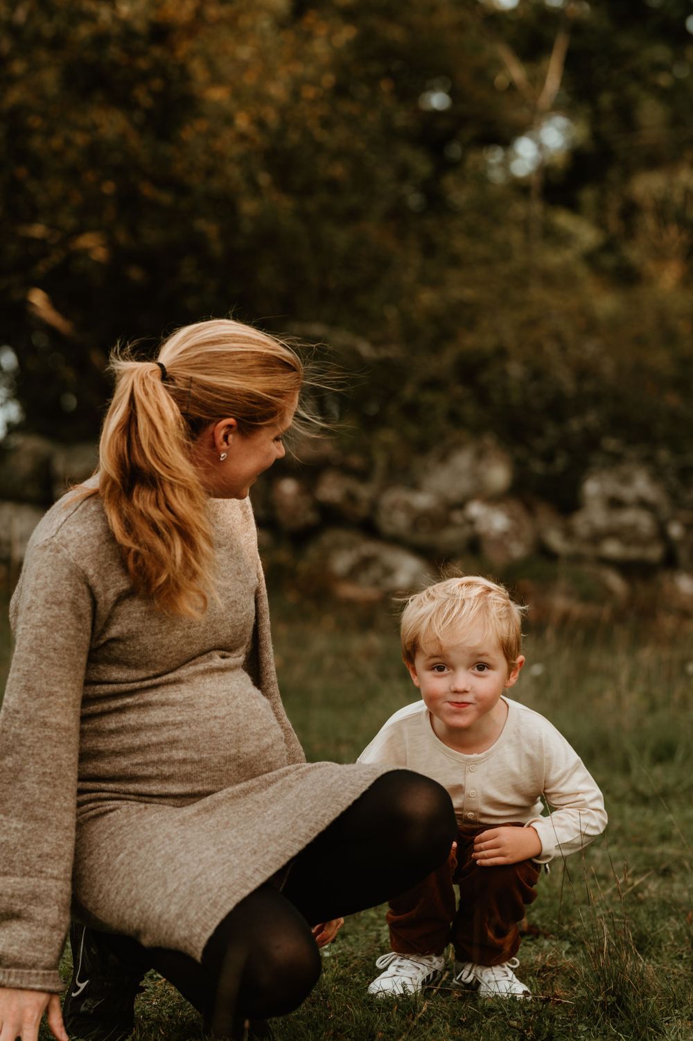 A touching outdoor moment between parent and child sitting in the grass during autumn.