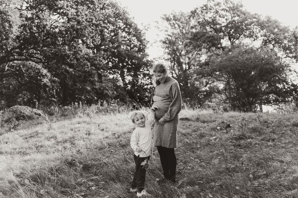 A black and white photograph of two people standing together on a grassy hillside.