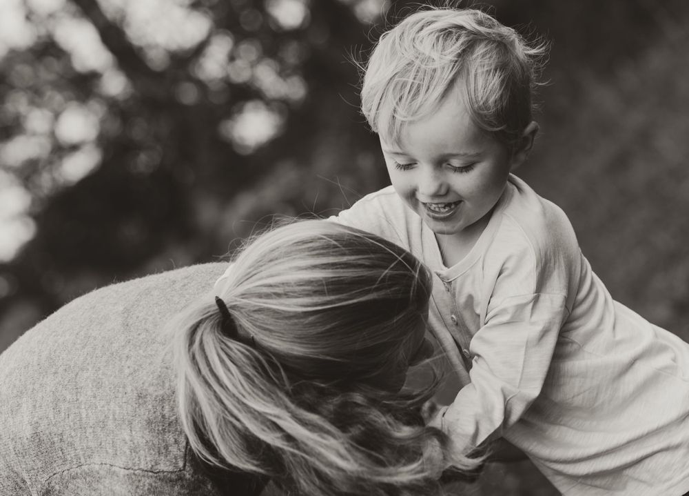 A joyful black and white candid moment between parent and child playing outdoors.