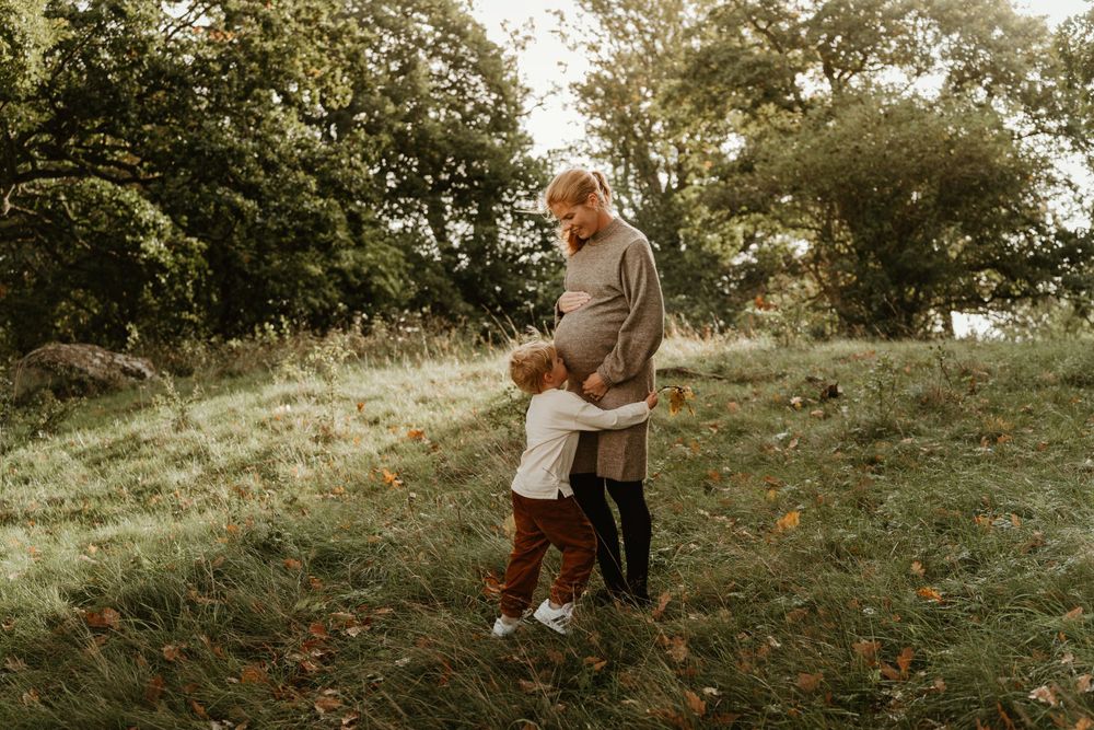 An intimate outdoor family moment captured in warm autumn tones with falling leaves.