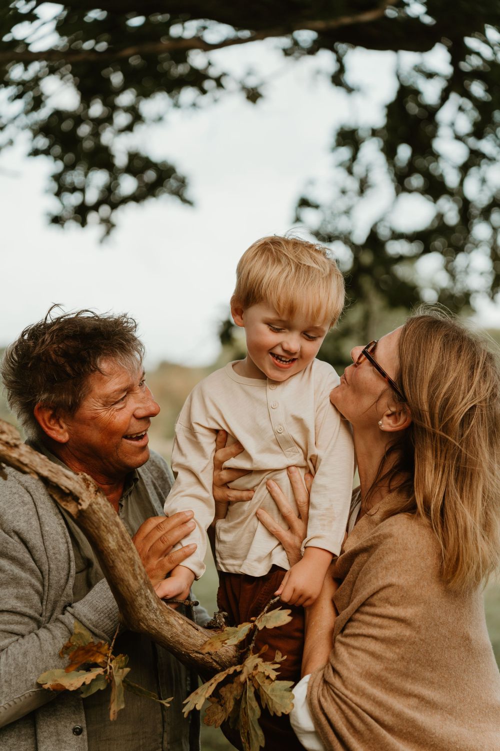 A happy outdoor family moment with everyone laughing together in warm autumn lighting.