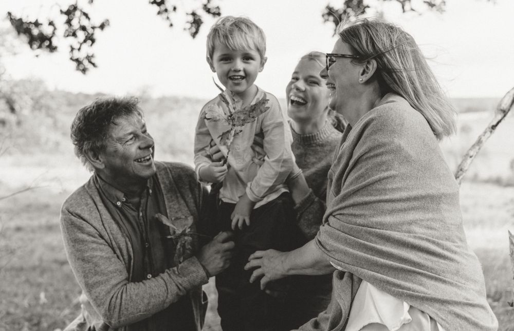 A candid black and white photo of a family sharing laughter outdoors.