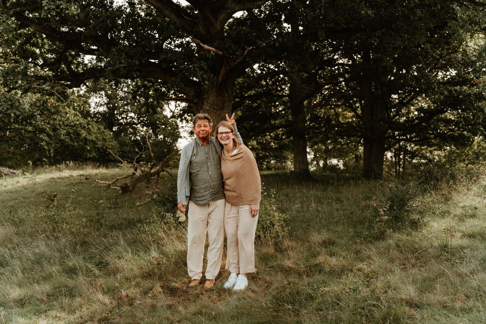 A couple poses together in a rustic outdoor setting during golden hour.