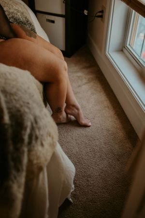 Intimate photo of legs and lace detail against carpet near sunlit window.
