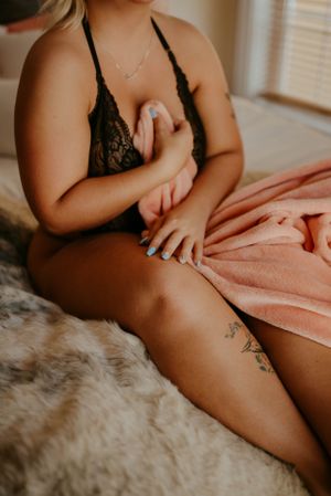 Intimate portrait showing black lace lingerie and delicate necklace against soft textures.