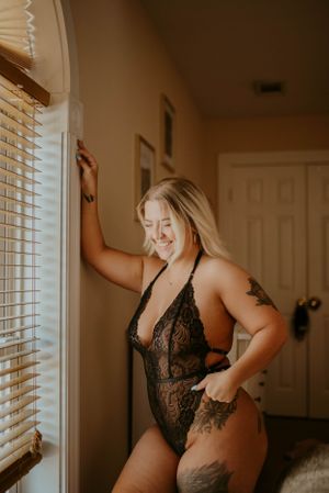 Candid boudoir portrait with warm lighting and natural poses by window.