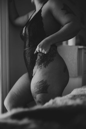 Monochrome boudoir photo focusing on tattoo art and lace lingerie details.