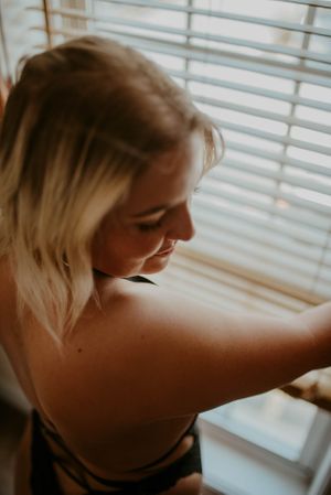 Intimate portrait in warm lighting by window with venetian blinds.