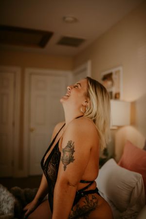 Natural light boudoir portrait showing tattoo art and black lace lingerie.