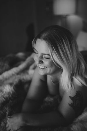 Black and white boudoir portrait capturing genuine laughter and natural beauty.