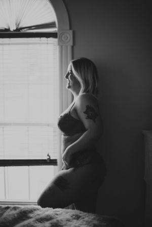 Silhouetted figure by arched window in dramatic black and white composition.