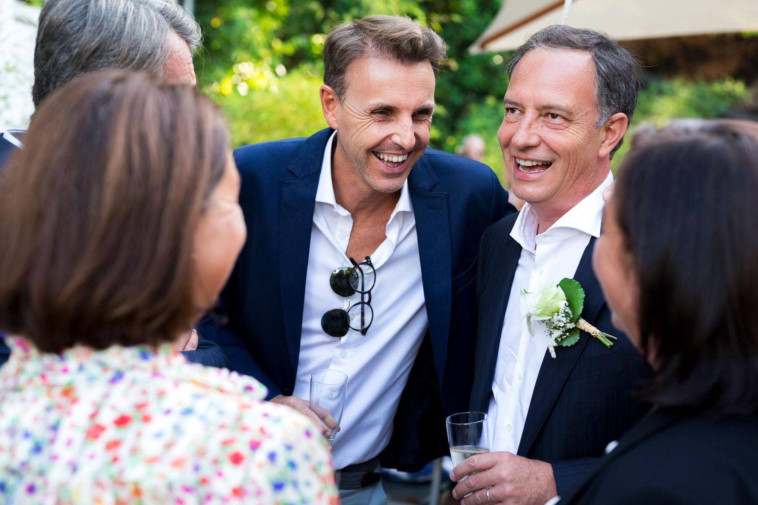 Guests engaging in lively conversation during an outdoor garden party or celebration.