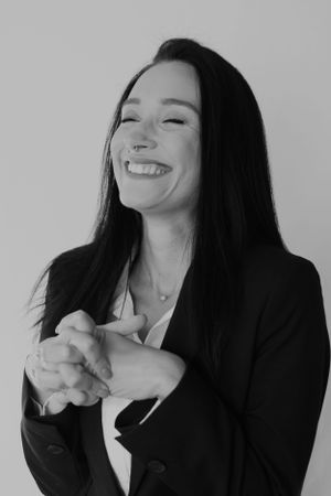 Black and white portrait showing joyful expression in professional attire.