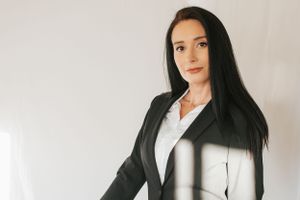 Professional studio portrait featuring classic business attire against white backdrop.