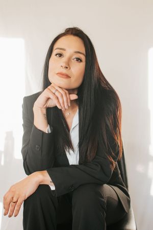 Professional portrait with thoughtful pose in business attire against light background.