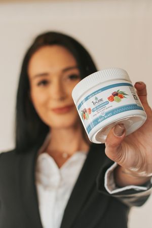 Professional displaying health supplement product container in business setting.