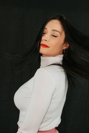 Artistic profile shot with flowing dark hair and white ribbed sweater.