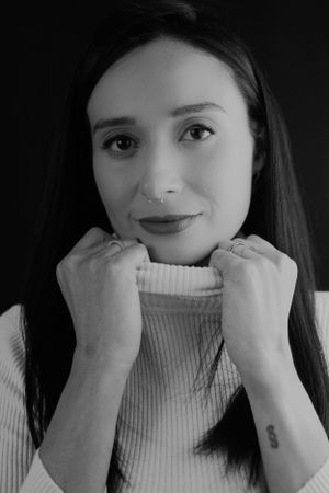 Monochrome portrait showing cozy turtleneck sweater and delicate nose piercing.