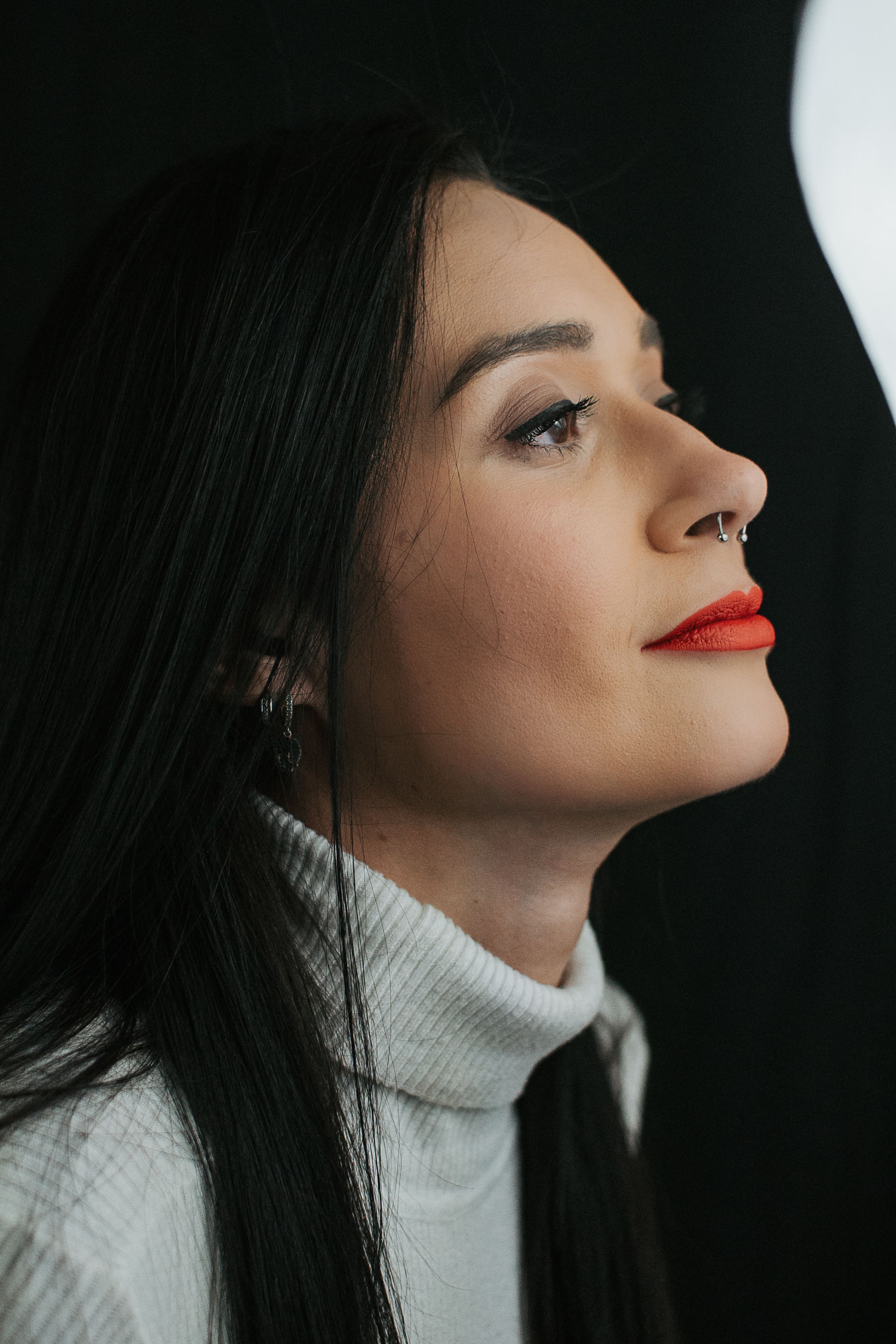 Artistic profile portrait featuring bright red lipstick and white turtleneck.