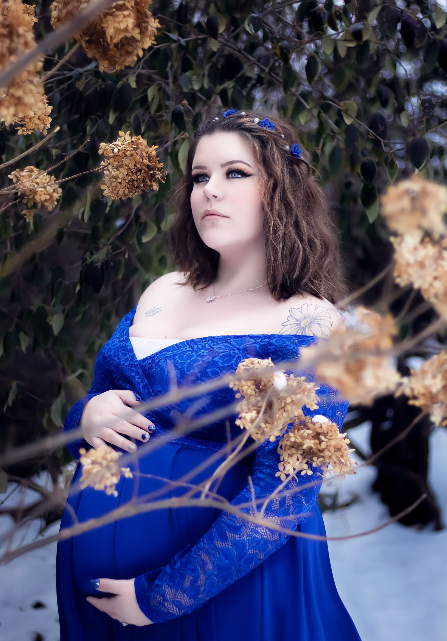 Dreamy portrait in a royal blue lace dress among dried hydrangea flowers.