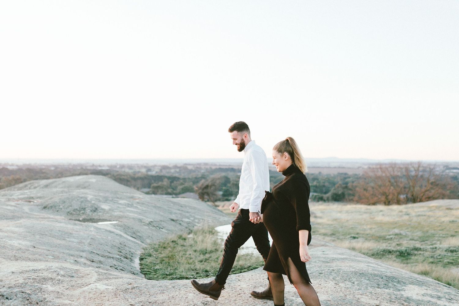 Two people climb together on rocky terrain with scenic views at sunset.
