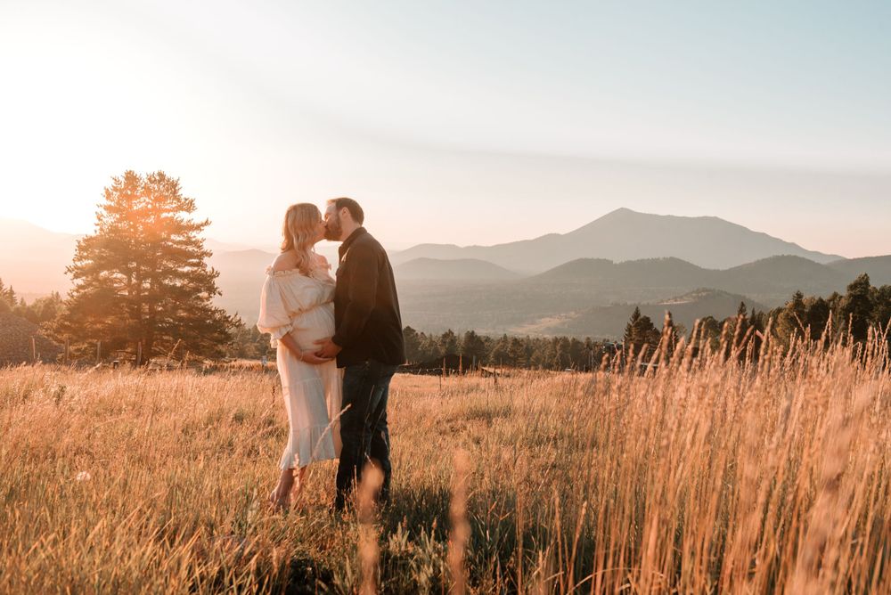 Silhouettes of people in a mountain meadow during golden hour sunset.