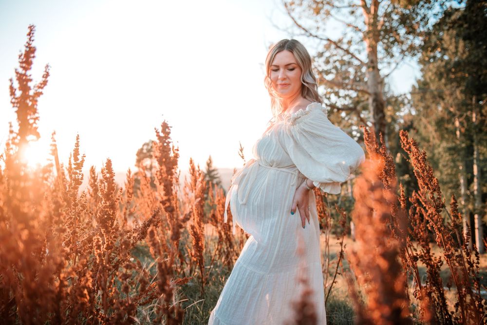 Ethereal sunset photography in a field of red wildflowers with a flowing white dress.