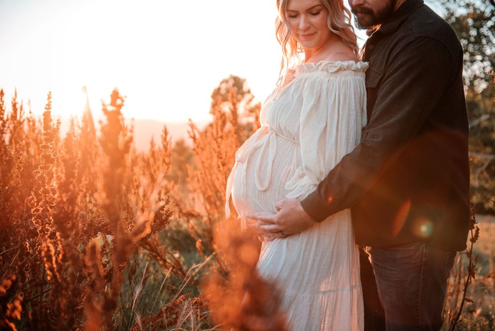 Romantic couple embraces in a field of red wildflowers during golden hour sunset.