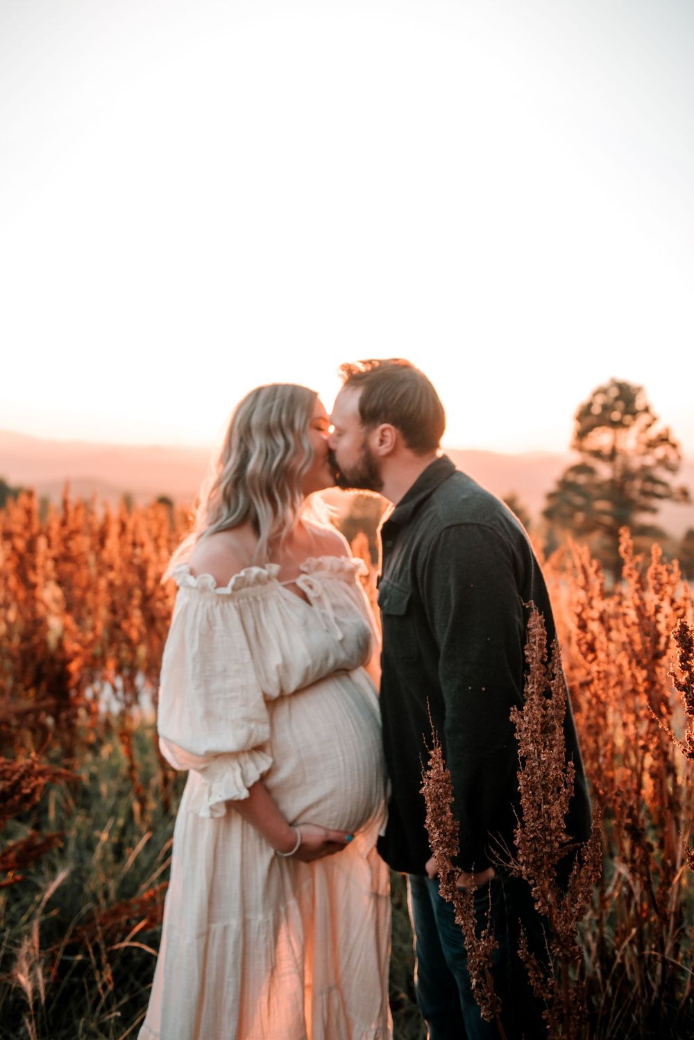 Loving embrace captured in golden sunset light among vibrant red wildflowers.