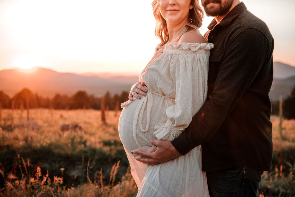 Maternity photo session in golden hour light with mountains in background.