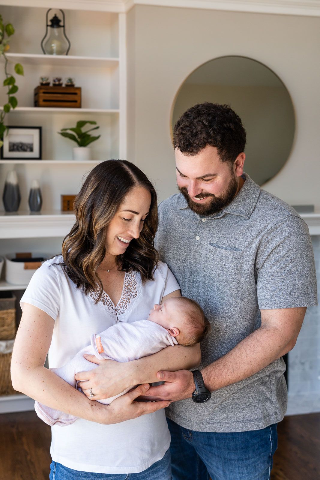Parents gazing lovingly at their daughter at an in home newborn photo session.