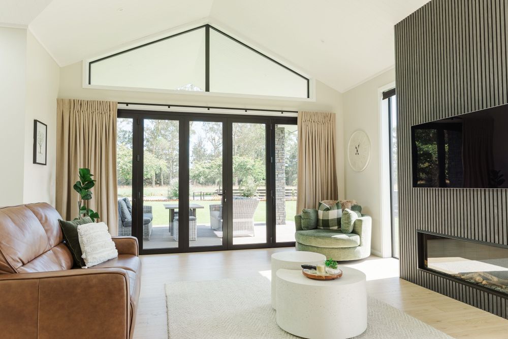 Modern living room with high ceilings, glass doors, brown leather sofa and contemporary decor.