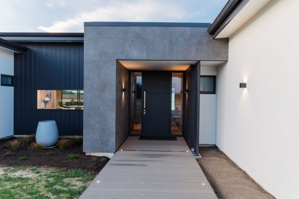Contemporary home entrance with concrete path and dark accent wall.
